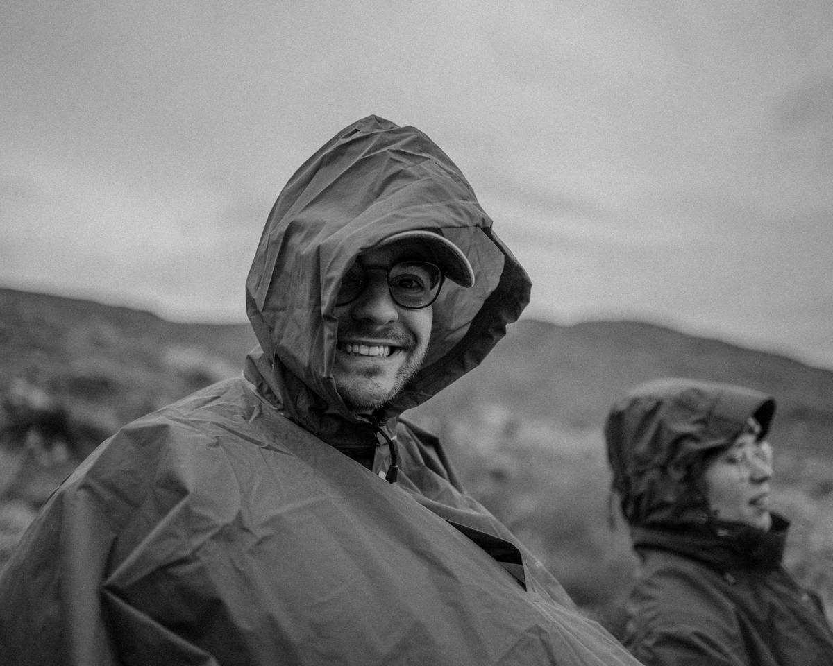 Side-by-side comparison of a high-performance water-repellent rain poncho (left) vs. a thin disposable PVC poncho (right) showing water beading on the left and soaking through on the right